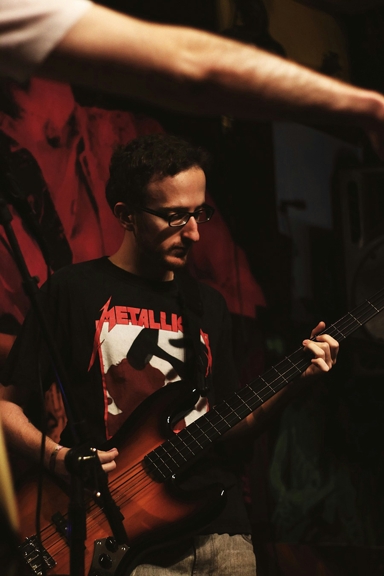 A man in a Metallica shirt playing guitar on stage